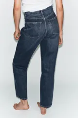 Jeans de tiro alto con corte mom fit, cinco bolsillos y cierre frontal con cremallera y botón metálico.