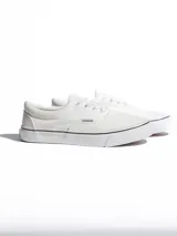 Championes de lona color blanco con cordones al tono y suela de goma blanca con una fina línea negra. Presenta etiqueta con logo de la marca en el lateral.