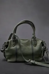 Cartera de cuero verde militar con acabado gastado, cuerpo blando, asas de mano, bolsillos frontales con cierre y tiras colgantes.