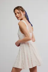 Vestido corto de poliéster color blanco con tejido calado tipo eyelet, sin mangas, con pronunciado escote en V, cuerpo ajustado y falda acampanada.