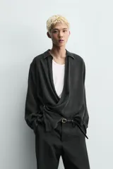 Camisa de corte relajado confeccionada en tejido fluido con mezcla de viscosa y lyocell. Presenta cuello polo, manga larga con puños abotonados y un diseño cruzado con cierre frontal de botones.