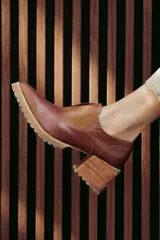 Zapato de cuero color beige, con taco de madera y suela dentada. Presenta un diseño slip-on con detalles de textura en relieve en los laterales y el empeine.