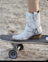 Bota estilo tejana de cuero vacuno color bordó, con detalle de argolla metálica y remaches decorativos.