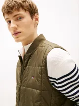 Chaleco verde militar acolchado con diseño geométrico de cuadros, cuello estilo béisbol, cierre de cremallera y logo de Tommy Hilfiger bordado en el pecho.