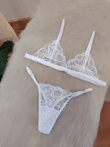 Conjunto de lencería compuesto por un bralette triangular de encaje floral con breteles regulables y una bombacha tipo tanga de encaje a juego con laterales ajustables.