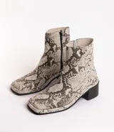 Botín de cuero con estampado de piel de serpiente en tonos blanco y negro, con puntera cuadrada y tacón bloque bajo.