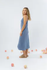 Vestido midi celeste de tejido tipo seda fría, con breteles finos regulables, botones de madera decorativos en el frente, pliegues decorativos en la cintura y cierre invisible en el costado.