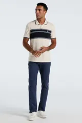 Polo de manga corta Original Penguin confeccionada en tejido interlock, color beige con franja horizontal central en azul marino y detalles en celeste. Presenta cuello clásico con botones y logo bordado en el pecho.