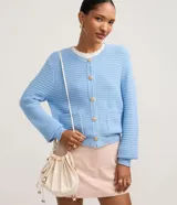 Cardigan de punto texturizado color celeste claro, con cuello redondo, cierre frontal de botones dorados y dos bolsillos delanteros tipo parche.