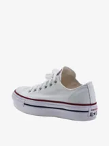 Championes Converse modelo Chuck Taylor All Star Lift Ox, de corte bajo con plataforma. Confeccionados en lona blanca, cuentan con puntera de goma, cordones al tono y la clásica suela con franjas decorativas en rojo y azul.