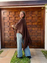 Ruana tejida en color chocolate, confeccionada en lana, con diseño de textura lisa y terminaciones con flecos largos en los extremos.