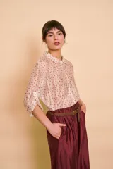Camisa de manga larga con estampado floral sutil en tonos rosados sobre base beige, cuello camisero clásico y cierre frontal de botones.