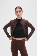 Campera deportiva de ajuste entallado, confeccionada en poliéster color gris oscuro. Presenta cuello alto, cierre frontal completo y mangas largas con aberturas para los pulgares.