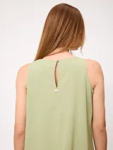 Vestido midi sin mangas de corte recto y holgado, color beige, con cuello redondo y bolsillos laterales.