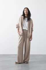 Pantalón de corte holgado y pierna ancha, con cintura elástica ajustable mediante cordón. Presenta bolsillos laterales y costuras verticales decorativas que recorren el frente de las piernas.