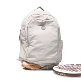 Mochila deportiva color gris, confeccionada en material textil con acabado arrugado. Presenta compartimento principal con cierre doble, bolsillo frontal con logo circular, compartimento inferior independiente para calzado y bolsillos laterales. Incluye tirantes ergonómicos ajustables y espaldera acolchada con malla transpirable.