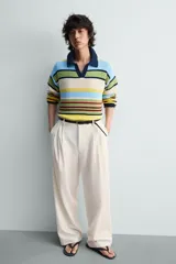 Sandalia tipo ojota o chancleta de goma, con base de color verde oscuro y tiras negras. Presenta una suela plana.