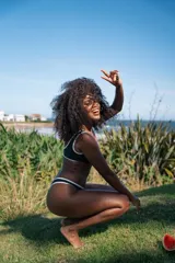 Conjunto de bikini negro con ribetes blancos, compuesto por un corpiño deportivo con logo y una bombacha clásica.