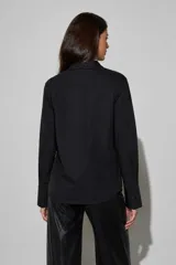 Camisa negra de manga larga con cuello clásico y detalle de strass brillante en el frente.