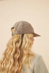 Gorra con visera confeccionada en lana fina sin teñir, con un sutil patrón de tejido en espiga.