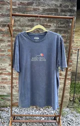 Remera azul con efecto lavado, de corte holgado y manga corta. Estampa en la espalda con flores de colores y la frase "Más flores, menos drama".