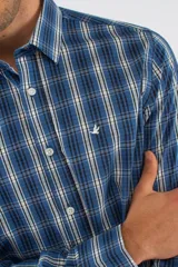 Camisa de manga larga con diseño de cuadros en tonos azules, blancos y negros. Presenta cuello clásico, cierre frontal con botones y logo bordado en el pecho. Corte semi slim.