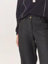 Pantalon de corte recto y tiro medio, confeccionado en tejido de lana con sutiles rayas verticales. Presenta bolsillos traseros aplicados, costuras reforzadas en las rodillas y ruedo con dobladillo.