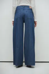 Pantalón palazzo de jean azul con rayas verticales blancas.