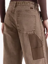 Pantalon de jean de corte wide leg en color marrón, con diseño de parches en tonos contrastantes y estilo carpintero. Presenta bolsillos diagonales frontales y bolsillos plaque en la parte posterior.