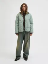 Campera acolchada de color gris oscuro, con diseño matelaseado de ondas, cuello alto en rib, cierre frontal con cremallera metálica y bolsillos frontales aplicados.