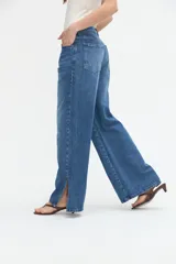 Jean wide leg color azul medio, con amplitud de piernas y tajo en el bajo.