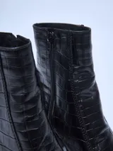 Bota corta negra con textura símil cuero de cocodrilo, caña media, punta cuadrada, plataforma delantera y taco geométrico.