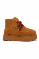 Bota corta de gamuza sintética color tostado con plataforma chunky de goma. Presenta cordones trenzados en color rojo y negro con pasadores metálicos dorados.