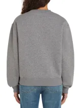 Buzo deportivo gris melange de corte regular con hombros caídos. Presenta el logo de Tommy Hilfiger en blanco centrado en el pecho y un pequeño logo bordado en la manga.