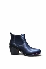Bota corta de cuero sintético color negro, con taco cuadrado y elásticos laterales tipo chelsea, decorada con tachas metálicas plateadas alrededor de las costuras.