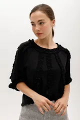Blusa negra de algodón suave con mangas 3/4 y escote redondo. Presenta volados en 3D en el frente, las mangas y el escote.