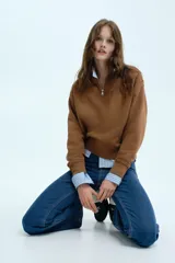 Jean de tiro alto con corte acampanado desde la rodilla, confeccionado en denim con leve stretch. Presenta cierre frontal de botones y diseño clásico de cinco bolsillos.