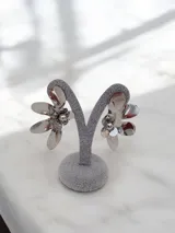Aros colgantes con diseño de flor metálica plateada de pétalos grandes y brillantes.