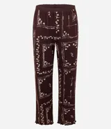 Pijama de dos piezas estilo americano en color bordó con estampado floral. La blusa es de manga larga, con cuello solapa, cierre frontal abotonado y terminaciones onduladas en los puños. El pantalón es largo y de corte recto.