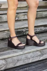 Sandalias de cuero color marrón chocolate con plataforma y taco corrido. Tira ancha sobre los dedos y tira al tobillo con hebilla dorada.
