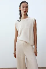 Top de punto color crema, de cuello redondo y sin mangas.