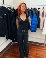 Pantalón negro de corte ajustado con cintura baja y hebilla plateada.