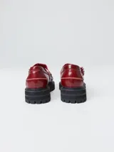 Zapato tipo guillermina de cuero color bordó, con diseño de mocasín, hebilla metálica y suela de goma con plataforma dentada.