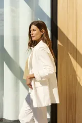 Blazer blanco de corte holgado, con solapas clásicas, bolsillos frontales con solapa y mangas largas con vuelta estampada a rayas.