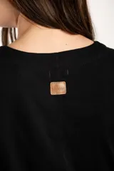 Remera de algodón negro con mangas cortas abullonadas, cuello redondo y costura central frontal.