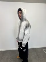 Buzo con capucha y cierre frontal, color gris con efecto lavado degradado. Presenta estampado gráfico en color blanco que recorre el pecho y las mangas, bolsillos laterales y etiqueta de marca en el puño.