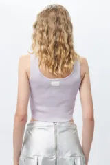 Top negro sin mangas con escote cuadrado, confeccionado en tejido con leve brillo y costuras asimétricas en el frente.