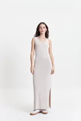 Vestido largo de punto color beige, con textura acanalada y escote redondo. De tiras finas y silueta al cuerpo, con tajo lateral.
