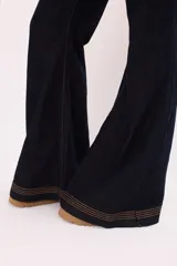 Pantalón jean de denim azul oscuro, corte wide leg, tiro medio y costuras a la vista en color ocre.