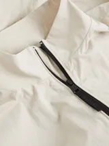 Campera Calvin Klein color beige claro, confeccionada en nailon arrugado reciclado. Tiene cuello alto, puños y bajo elásticos, cierre con cremallera, bolsillos con cremallera en la cintura, abertura de ventilación en la espalda, forro de poliéster reciclado e insignia con el logo de goma de Calvin Klein en la manga.